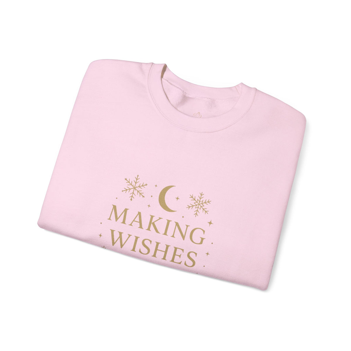 Folded light pink sweatshirt showing Making Wishes Come True moon and snowflake print