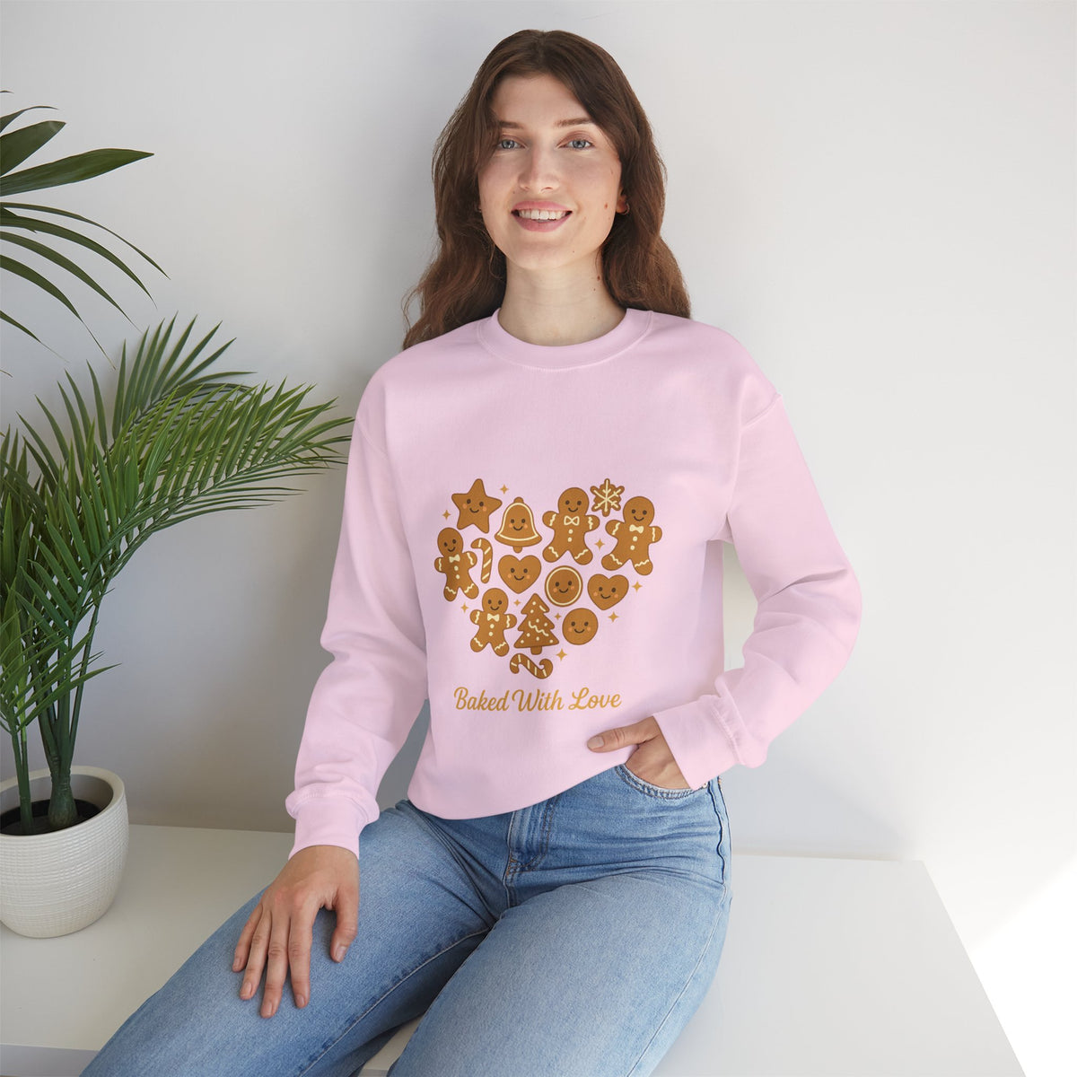 Model wearing a light pink Baked With Love gingerbread heart sweatshirt