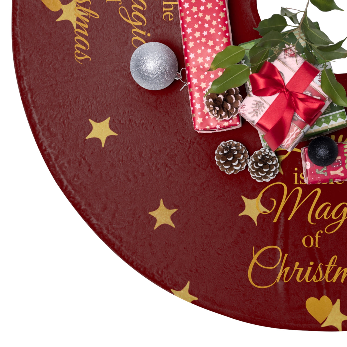 Close-up of the red and gold Christmas tree skirt beside wrapped gifts and festive greenery