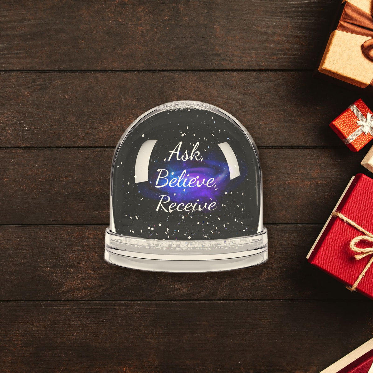 Ask Believe Receive Affirmation Snow Globe surrounded by wrapped Christmas gifts