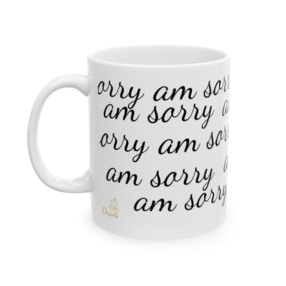 White ceramic mug with repeated “am sorry” text in cursive font and golden Druvs logo.