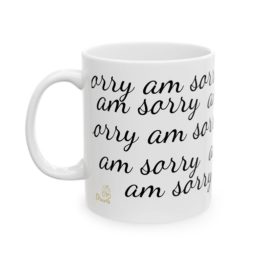 White ceramic mug with repeated “am sorry” text in cursive font and golden Druvs logo.
