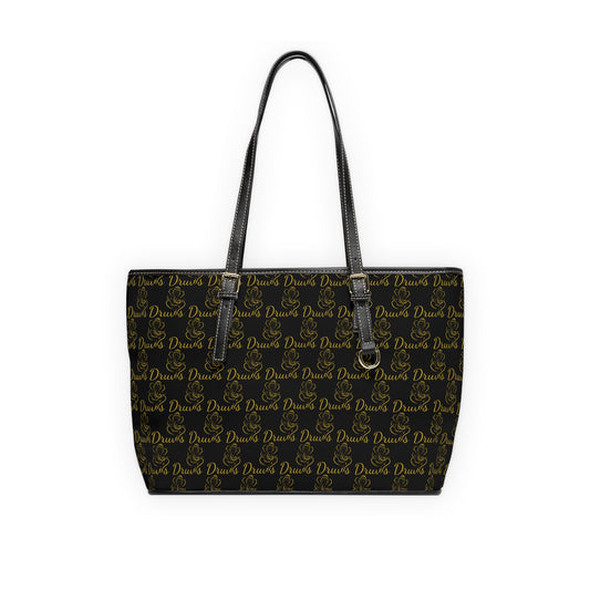 Black leather tote with repeating gold Druvs logo and Ganesha design, double shoulder straps and zip closure.