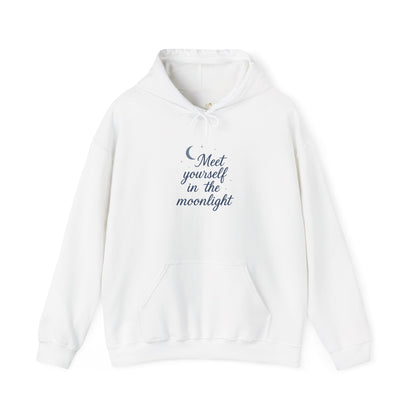White hoodie with soft blue text: “Meet yourself in the moonlight” and a small crescent moon above. Spiritual and minimalist winterwear.